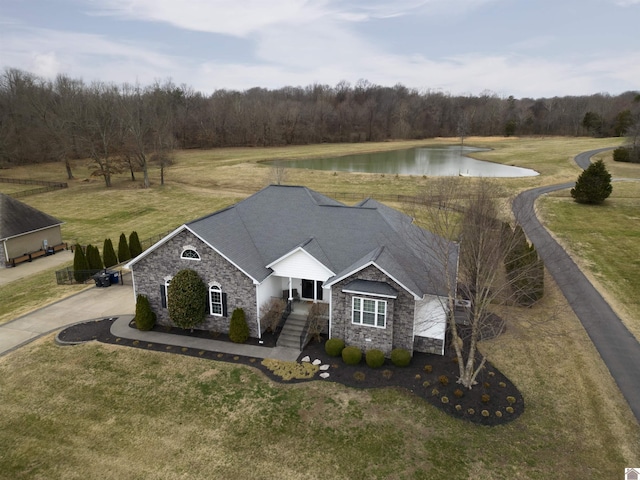 view of front of home featuring a water view, roof with shingles, a front yard, stone siding, and driveway