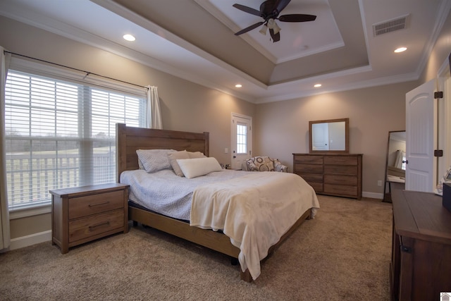 bedroom featuring visible vents, baseboards, a tray ceiling, crown molding, and light colored carpet