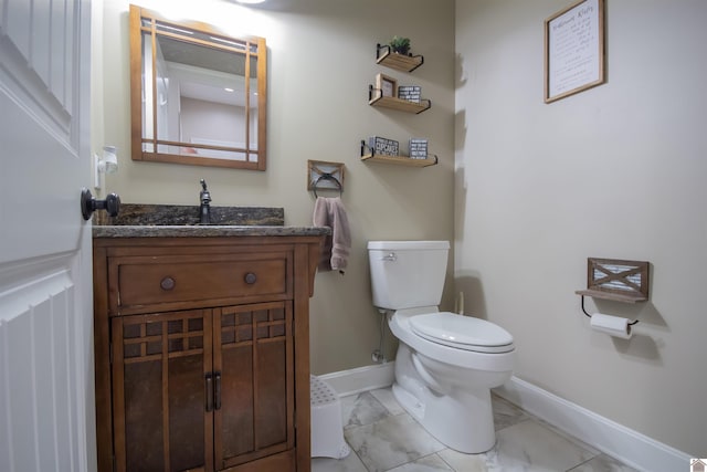 half bath featuring marble finish floor, toilet, vanity, and baseboards