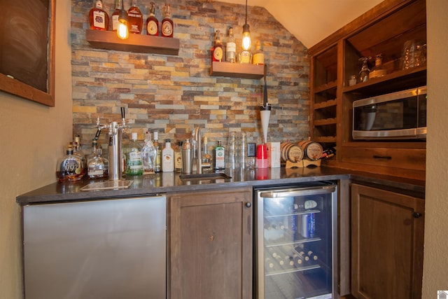 bar with stainless steel microwave, wine cooler, a dry bar, vaulted ceiling, and a sink