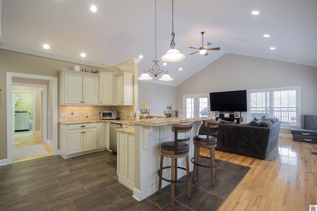 kitchen featuring backsplash, open floor plan, light stone counters, washer / dryer, and a peninsula