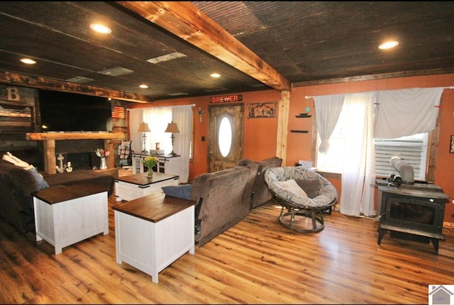 living room featuring recessed lighting, a fireplace, a wood stove, and wood finished floors