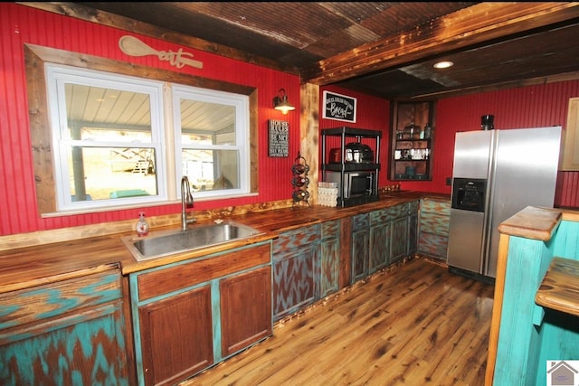 kitchen with butcher block counters, wood finished floors, appliances with stainless steel finishes, and a sink