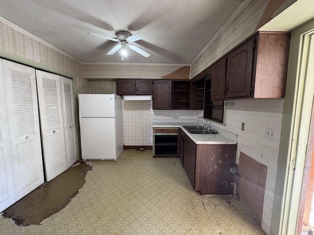 kitchen with light floors, open shelves, freestanding refrigerator, a sink, and crown molding