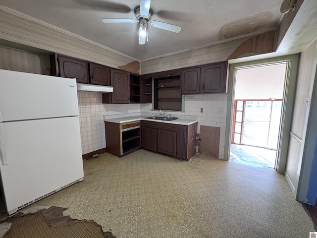 kitchen featuring open shelves, dark brown cabinets, freestanding refrigerator, and a sink