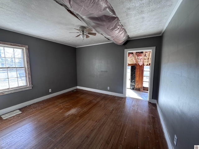 spare room with a ceiling fan, baseboards, ornamental molding, dark wood-type flooring, and a textured ceiling