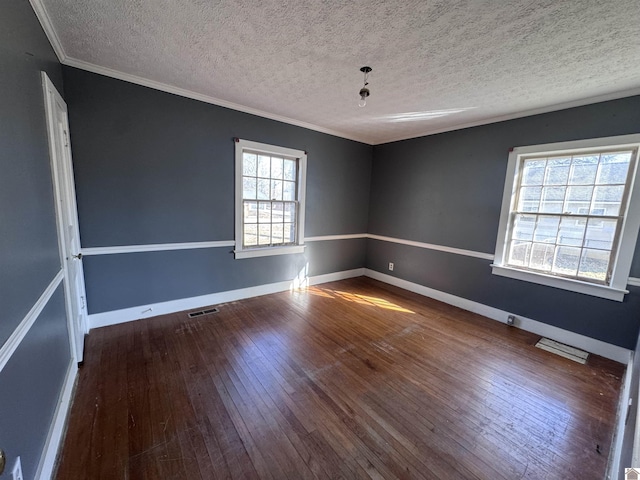 spare room with hardwood / wood-style flooring, crown molding, baseboards, and visible vents