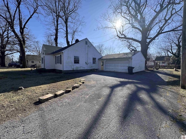 view of side of home with a chimney, a detached garage, and an outdoor structure