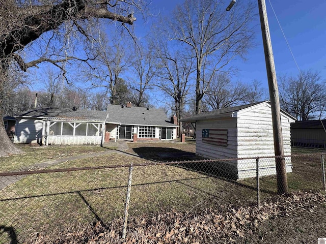 view of front of home featuring an outdoor structure, a fenced backyard, and a sunroom