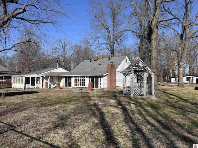 view of front of house with a gazebo, a chimney, and a front lawn