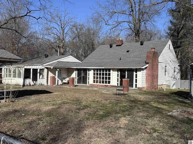 back of property featuring a yard, roof with shingles, and a chimney