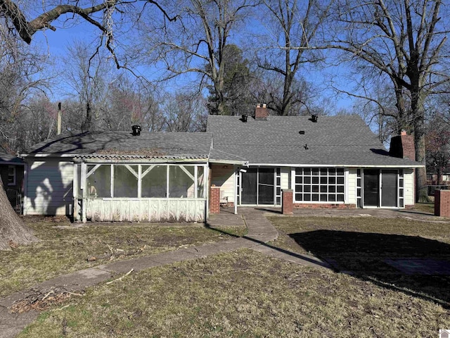 back of house with a shingled roof, brick siding, a sunroom, and a chimney