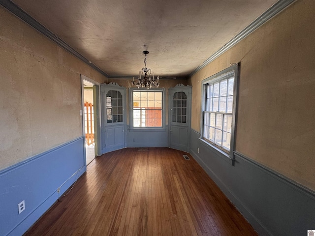 unfurnished dining area featuring hardwood / wood-style flooring, visible vents, a wealth of natural light, and ornamental molding