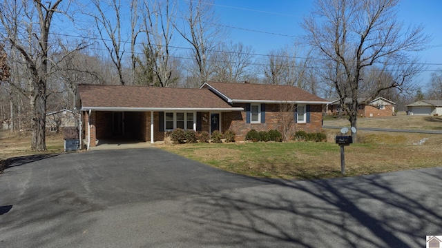 view of front of house with brick siding, aphalt driveway, a front yard, roof with shingles, and a garage