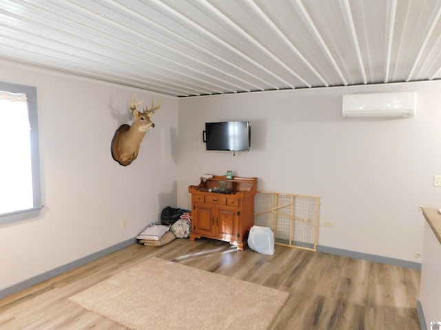 interior space featuring a wall mounted air conditioner, baseboards, and wood finished floors