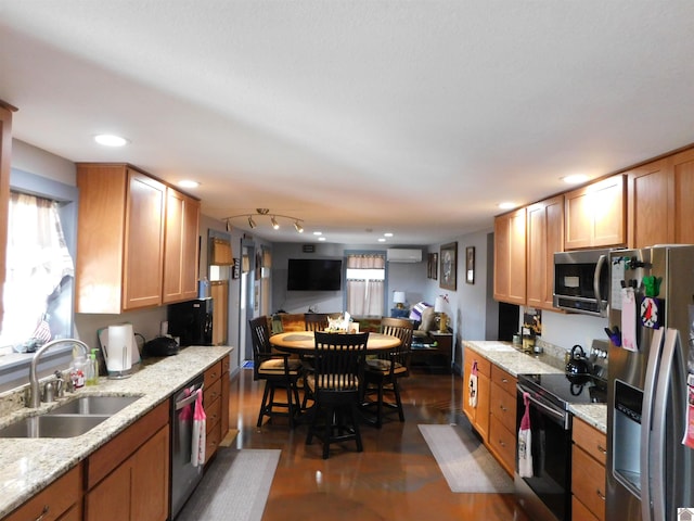 kitchen featuring light stone countertops, recessed lighting, a sink, an AC wall unit, and appliances with stainless steel finishes