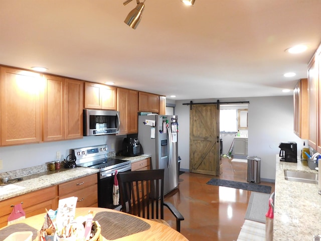 kitchen with recessed lighting, stainless steel appliances, a barn door, and a sink