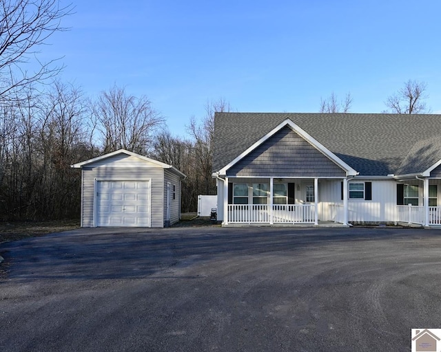 view of front of home featuring an outbuilding, aphalt driveway, covered porch, roof with shingles, and a garage