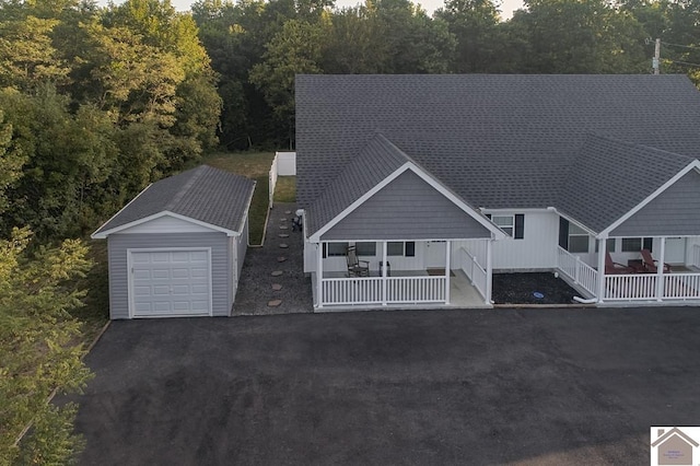 view of front of house featuring a shingled roof, a porch, a garage, an outbuilding, and driveway