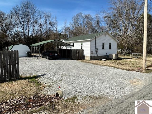 view of home's exterior with a carport, central air condition unit, driveway, and fence