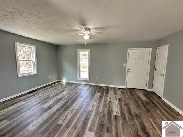 empty room featuring dark wood-style floors, a textured ceiling, baseboards, and a ceiling fan