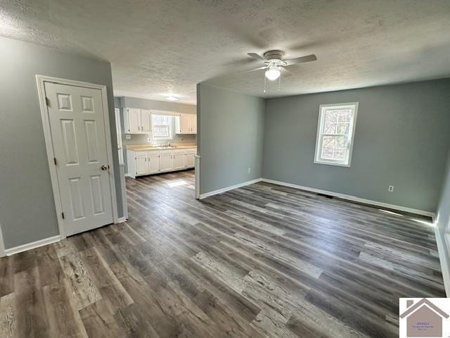 interior space featuring baseboards, ceiling fan, a sink, dark wood-type flooring, and a textured ceiling