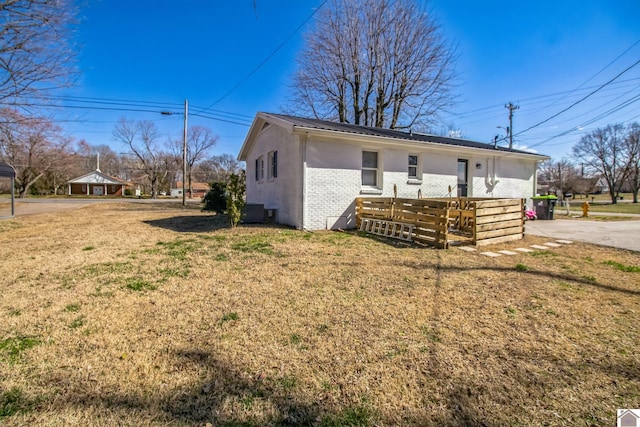 rear view of property with brick siding, a lawn, and metal roof