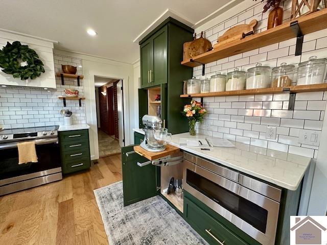 kitchen with open shelves, light countertops, light wood-style flooring, appliances with stainless steel finishes, and green cabinetry