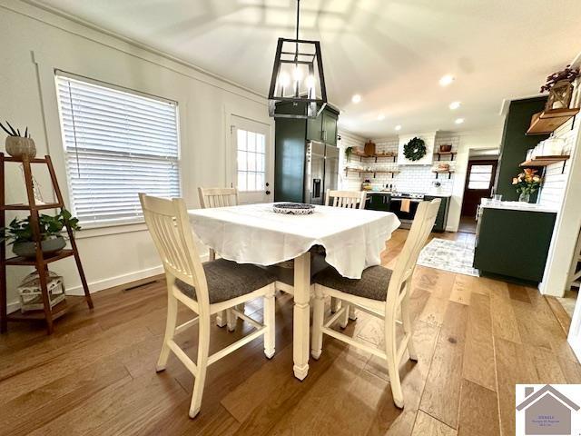 dining room with a wealth of natural light, light wood-style floors, and ornamental molding