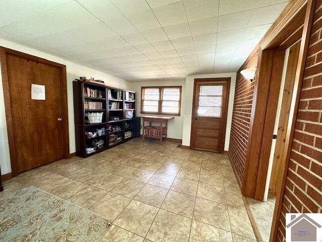 foyer with brick wall and baseboards