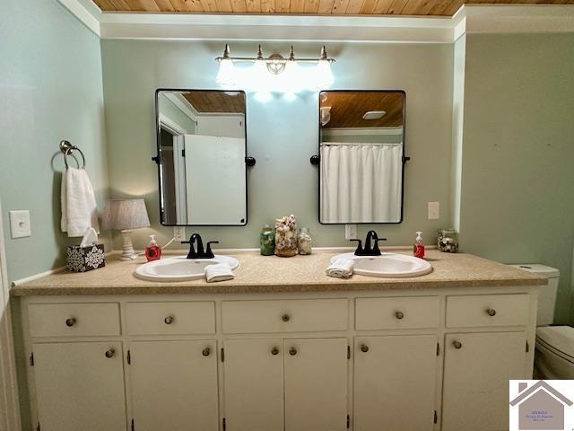 bathroom with double vanity, toilet, wood ceiling, and a sink