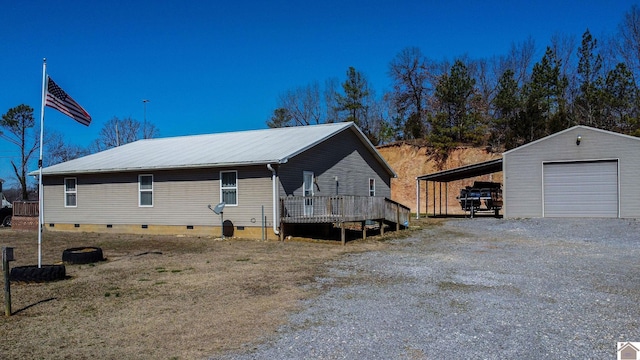 view of home's exterior with an outbuilding, driveway, a detached garage, metal roof, and crawl space