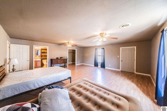 bedroom with a ceiling fan, wood finished floors, visible vents, baseboards, and a textured ceiling