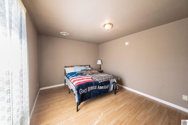 bedroom featuring light wood-style flooring, visible vents, and baseboards