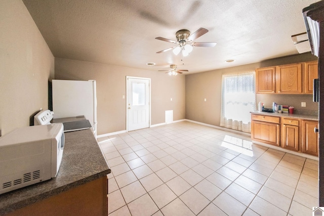 kitchen featuring light tile patterned floors, baseboards, white appliances, and a textured ceiling