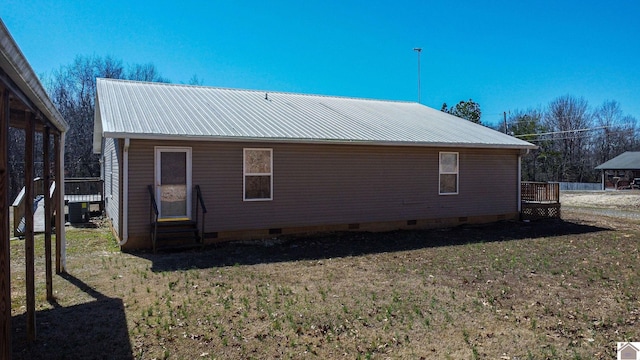 rear view of house featuring crawl space, metal roof, and a yard