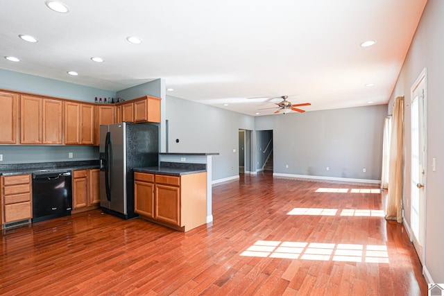 kitchen featuring black dishwasher, dark countertops, recessed lighting, stainless steel fridge, and light wood finished floors