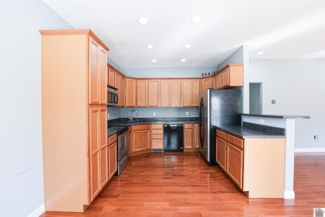 kitchen featuring dark countertops, appliances with stainless steel finishes, light wood-style flooring, and light brown cabinets