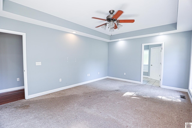 spare room with carpet, a ceiling fan, visible vents, and baseboards