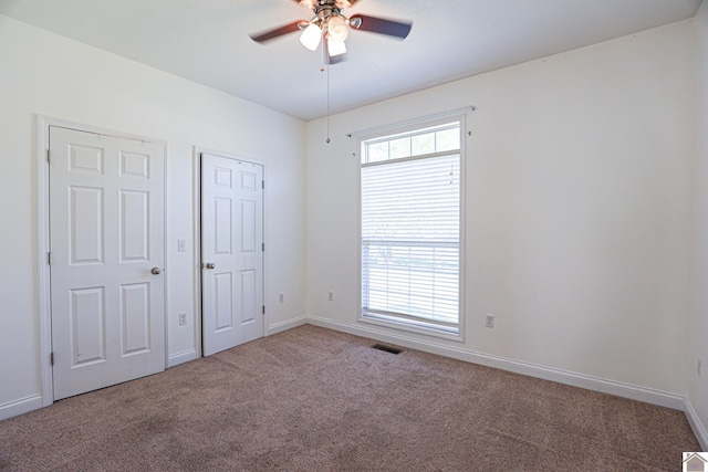 unfurnished bedroom with multiple windows, visible vents, baseboards, and carpet floors