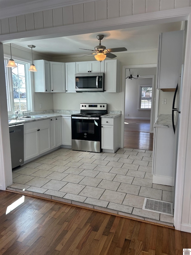 kitchen featuring light wood finished floors, visible vents, stainless steel appliances, white cabinetry, and a sink