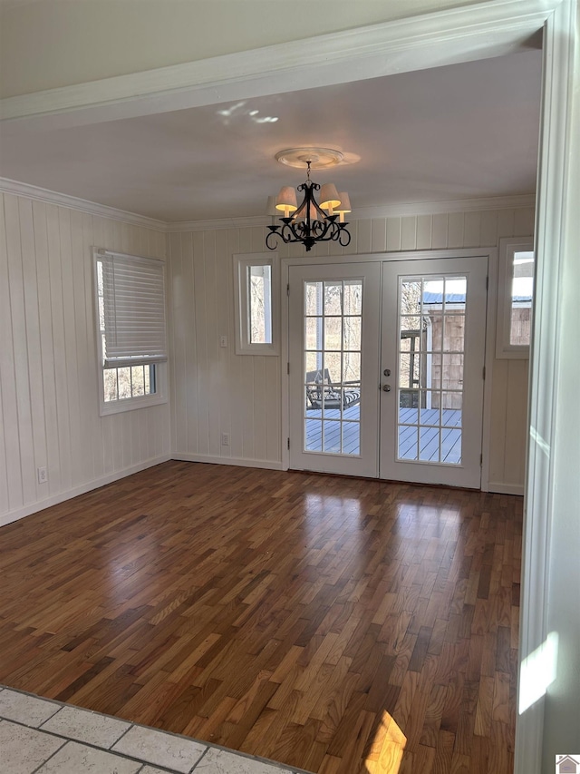 unfurnished room featuring dark wood finished floors, an inviting chandelier, french doors, and ornamental molding