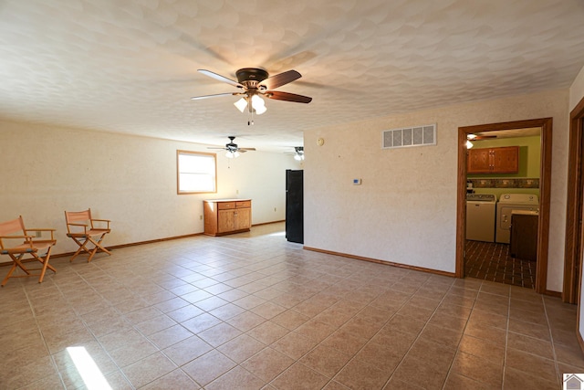 interior space featuring visible vents, baseboards, washing machine and dryer, tile patterned floors, and a textured ceiling