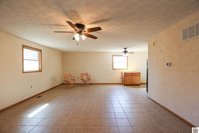 tiled spare room with a wealth of natural light, visible vents, and a textured ceiling