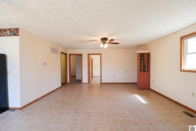 empty room featuring light tile patterned flooring, baseboards, visible vents, and a textured ceiling