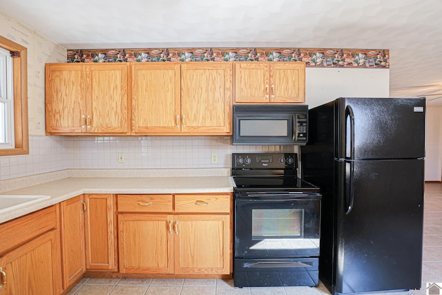 kitchen featuring light tile patterned floors, backsplash, black appliances, and light countertops