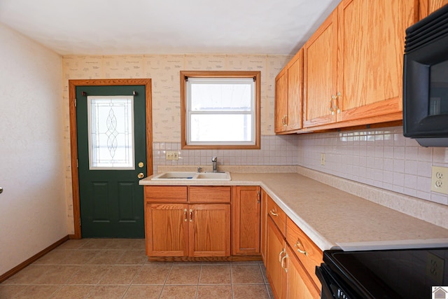 kitchen with light tile patterned floors, baseboards, a sink, light countertops, and black microwave