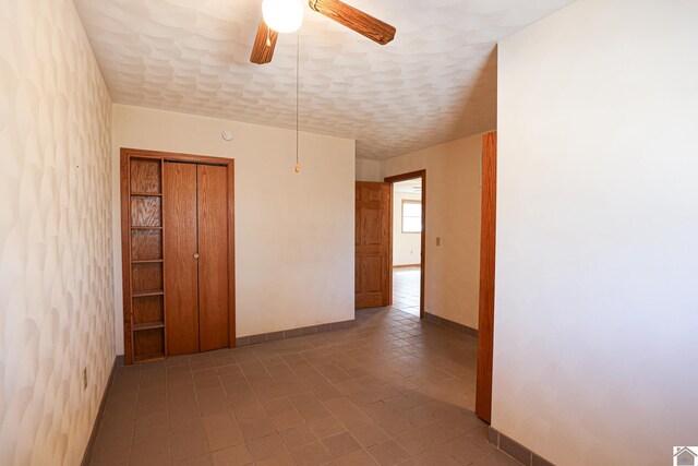 unfurnished room featuring a textured ceiling, baseboards, and ceiling fan