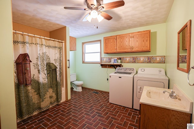 clothes washing area featuring a sink, washing machine and dryer, brick floor, ceiling fan, and laundry area