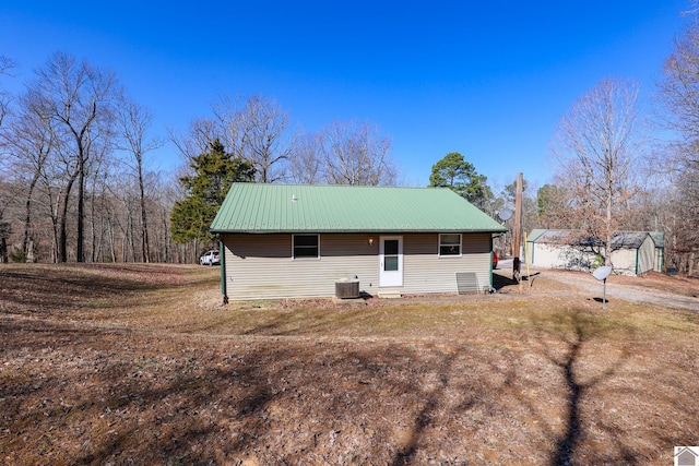 back of house featuring a storage shed, an outbuilding, cooling unit, and metal roof